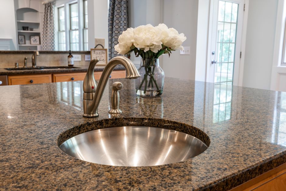 Stylish kitchen interior featuring granite countertop and a stainless steel sink.